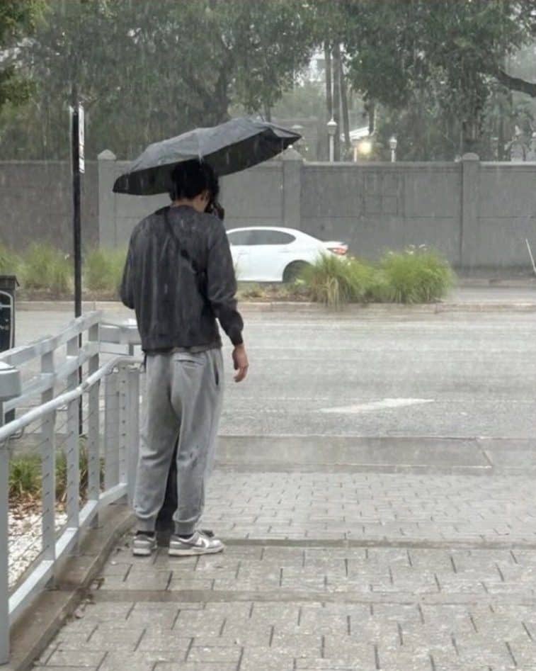 A man standing alone under an umbrella in heavy rain in Tampa