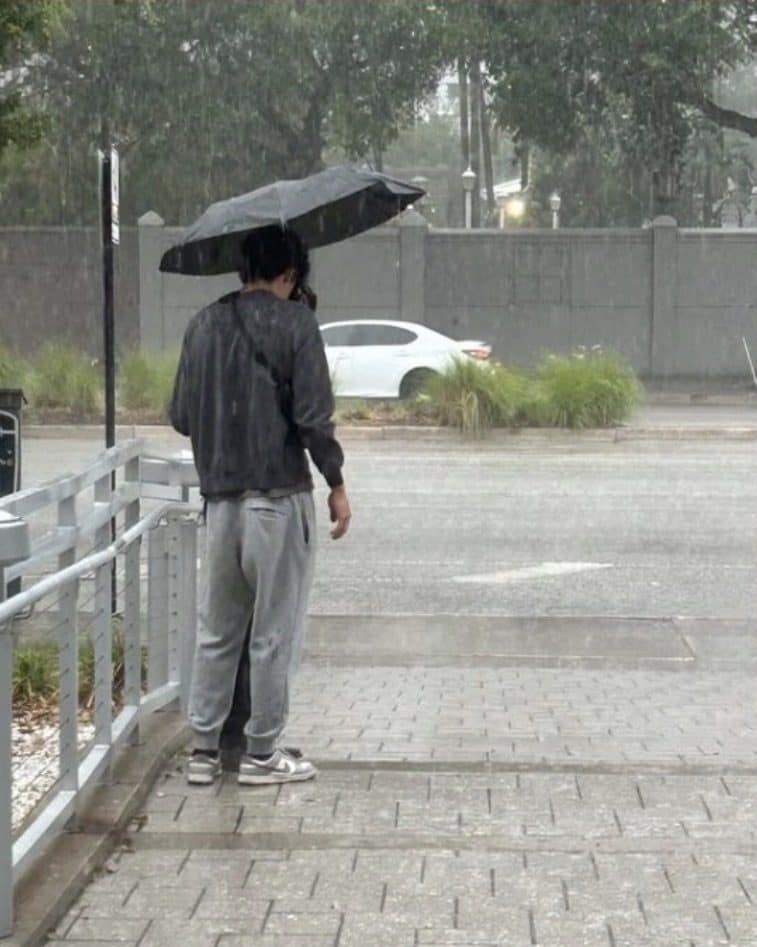 A man standing alone under an umbrella in heavy rain in Tampa