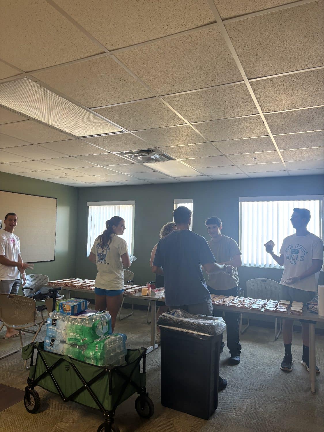 Volunteers assembling sandwiches on folding tables before an outreach